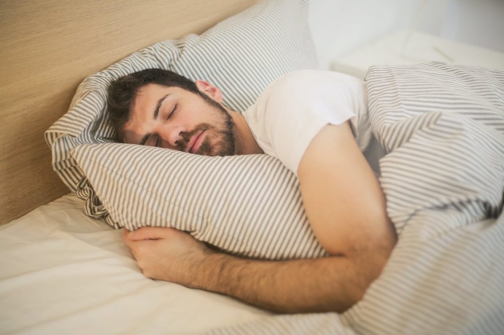 Man sleeping with a pillow in bed.